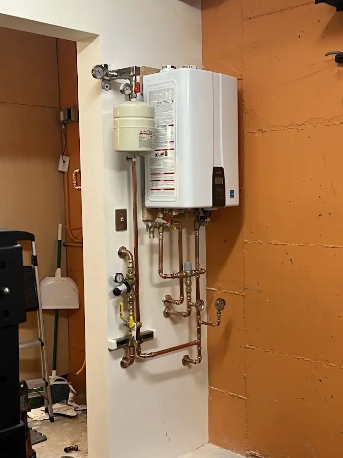 Plumbing technician inspecting water heater connections in Cannon